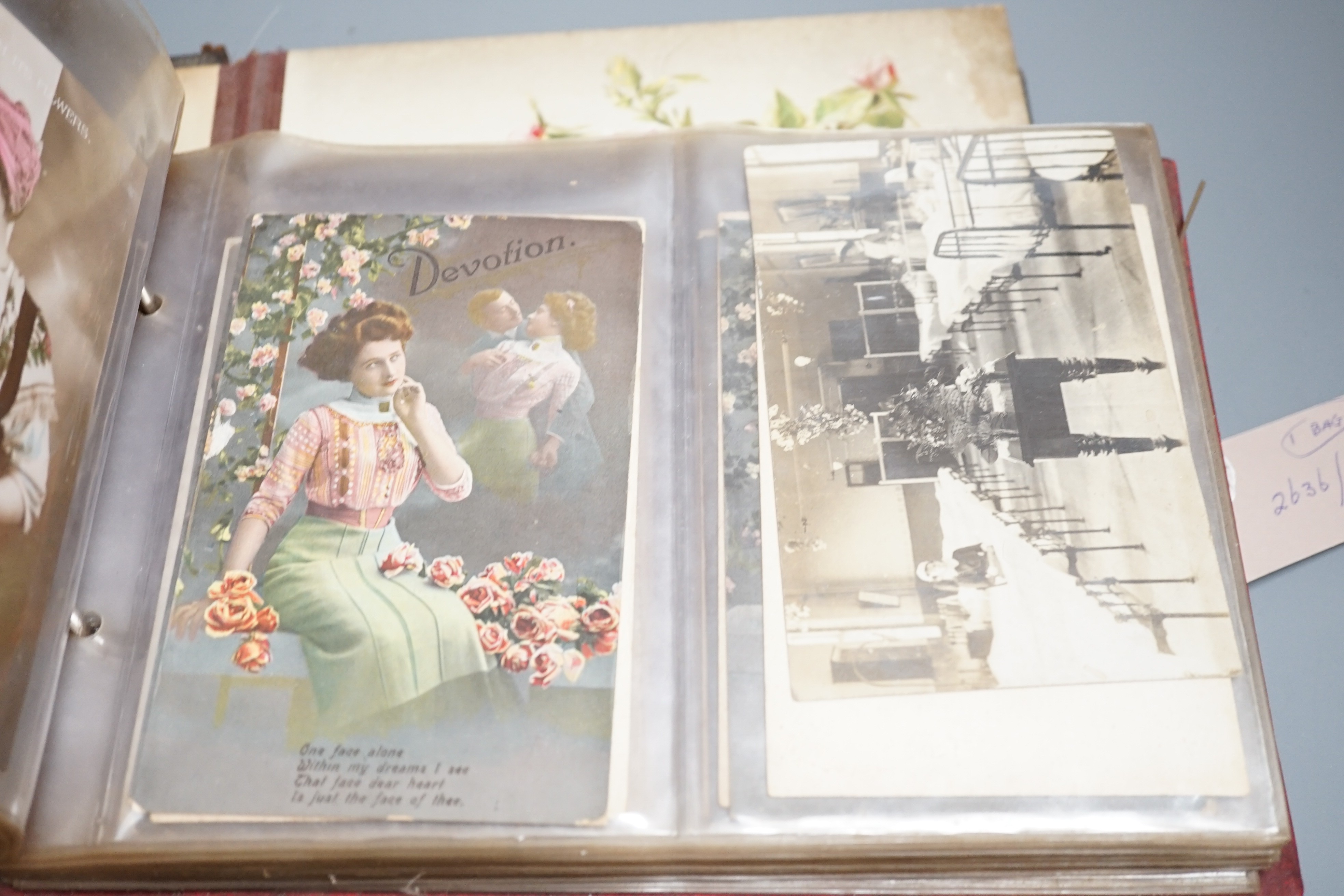 An early 20th century postcard collection in two albums and an empty late Victorian leather photo album